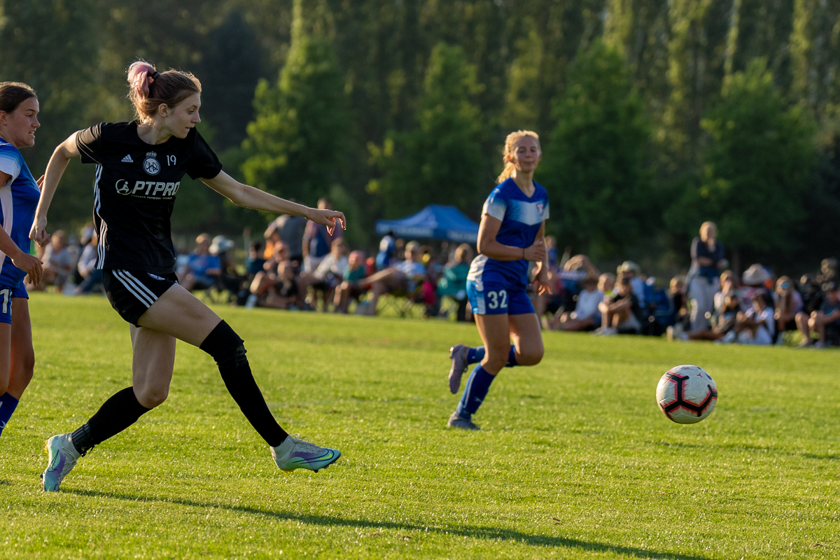 Female LWPFC player, wearing the club's all-black uniform, striking the ball at a summer tournament